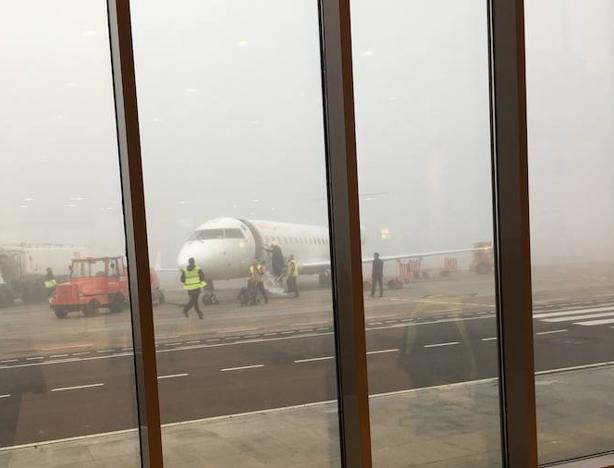 Avión entre la niebla visto desde la sala de embarque pacense. :: A.T.