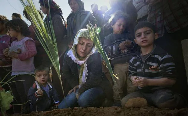 Una mujer kurda llora con su hijos la muerte de su marido ante su tumba, caído en la batalla de Kobane (Siria), en la que se enfrentaron el Estado Islámico y fuerzas de las Unidades de Protección Popular Kurdas (YPG). La imagen fue tomada en 2014. Los yihadistas fueron expulsados de la zona. 