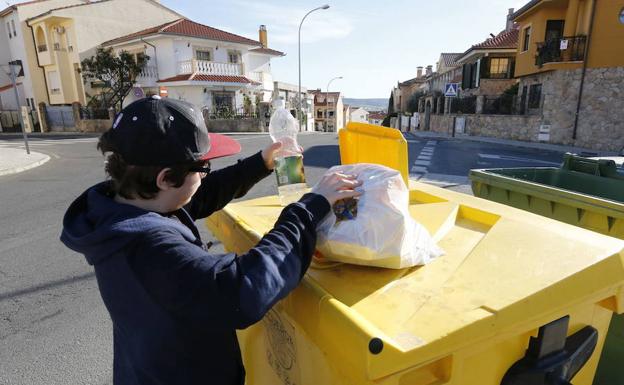 Un ciudadano de Plasencia deposita varios envases en el contenedor amarillo. :: 