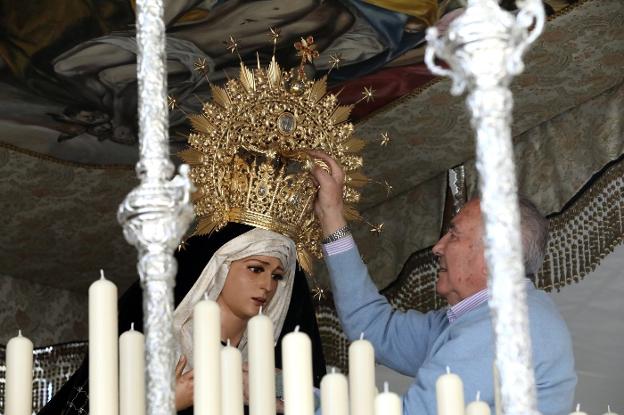 Un hombre le coloca bien la corona a Nuestra Señora del Mayor Dolor, que sale hoy. :: brígido