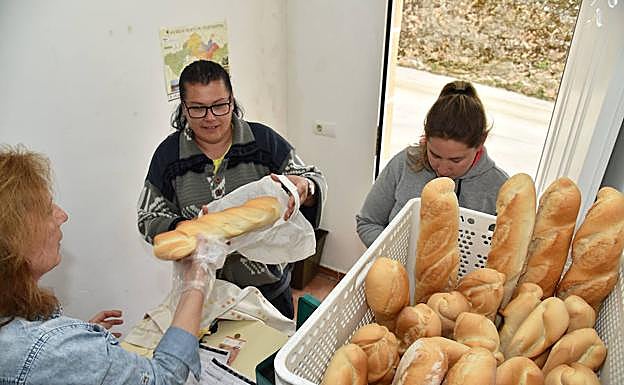 La alcaldesa de Gargüera despacha el pan a dos vecinas del municipio. 