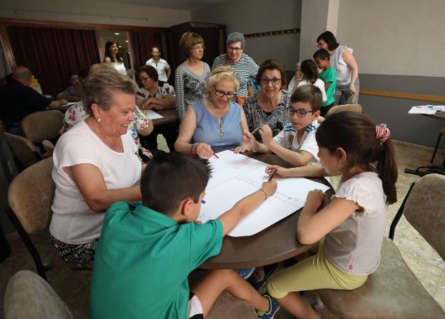 Niños y mayores comparten mesa y hacen un dibujo sobre los transportes. :: brígido