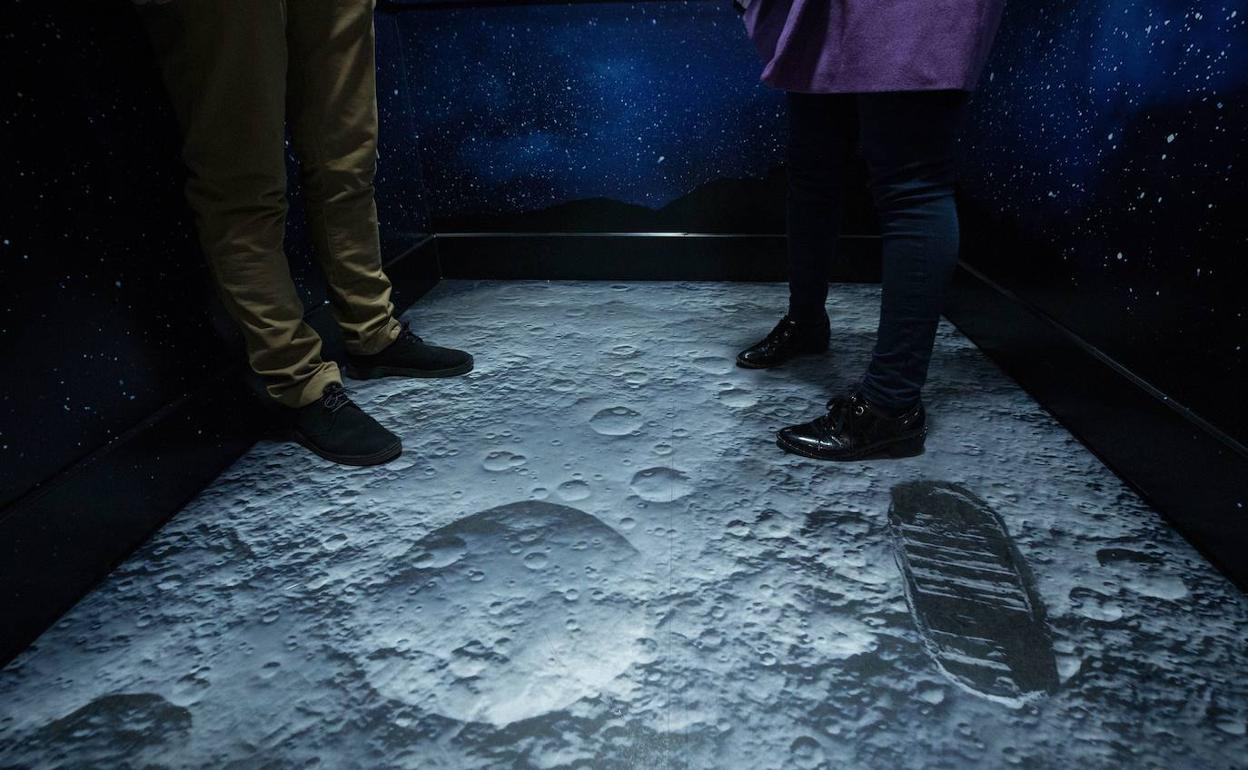 Dos personas caminan sobre una recreación de la pisada del astronauta estadounidense Neil Armstrong en la Luna en Santiago de Chile.