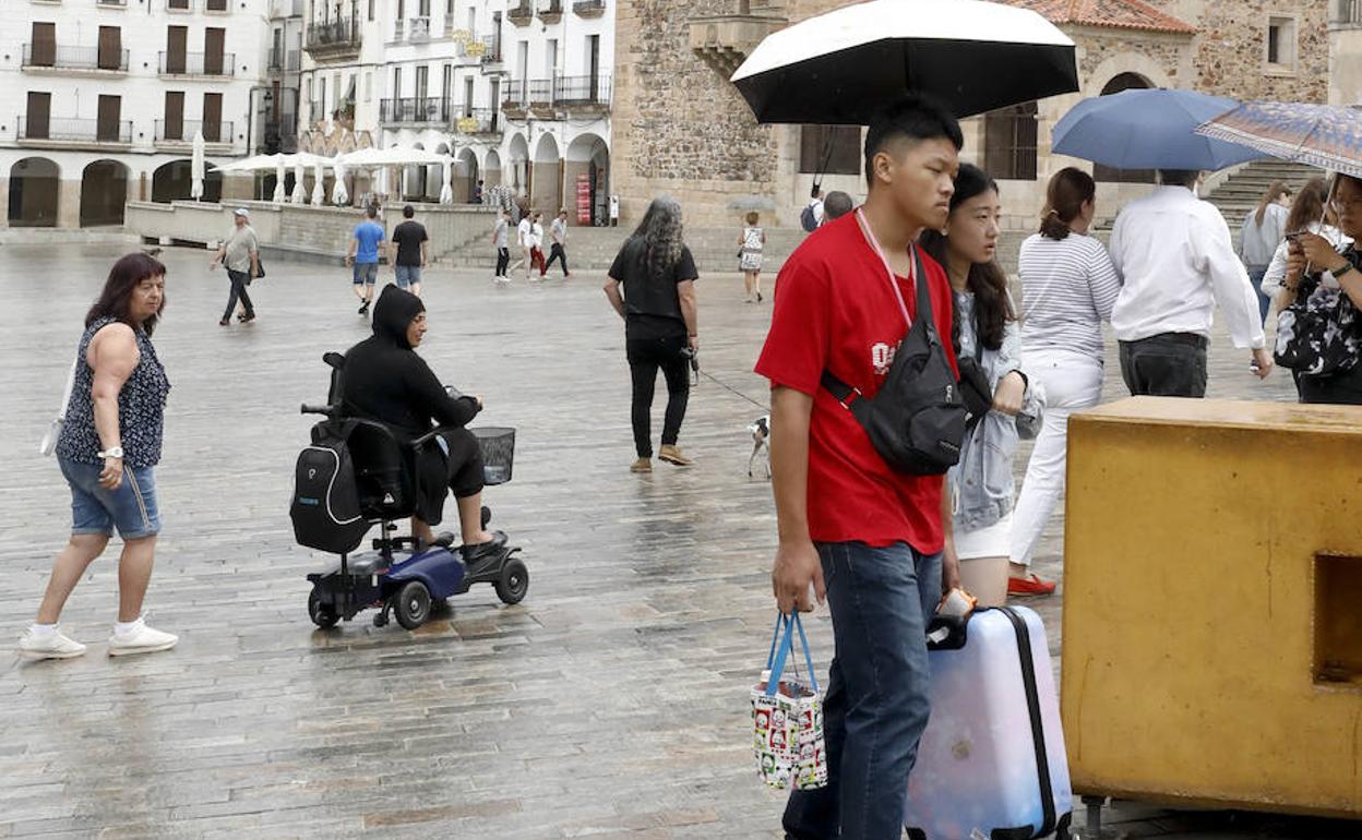 Turistas con paraguas este miércoles en la Plaza Mayor de Cáceres.