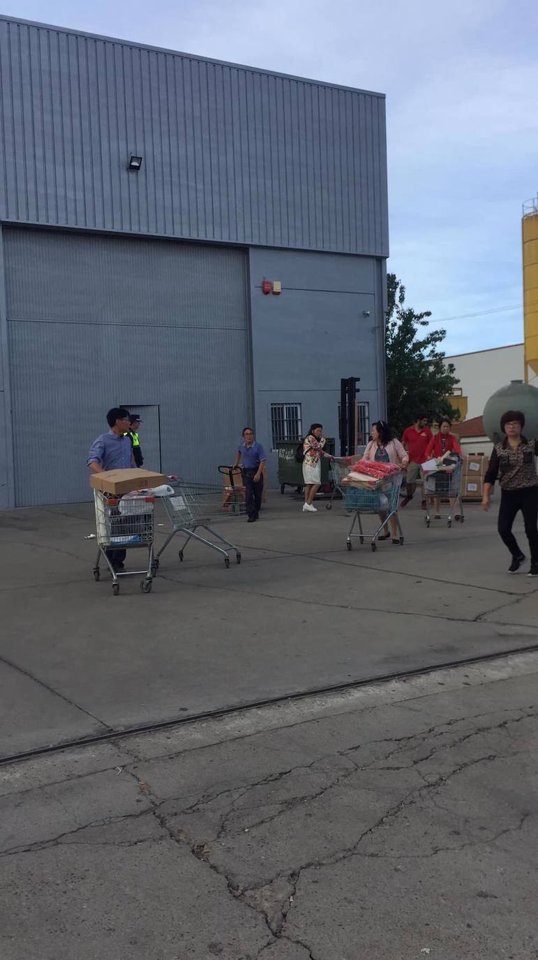 Trabajadores del bazar chino 'Las tres banderas' sacando material de la nave tras ser desalojados.