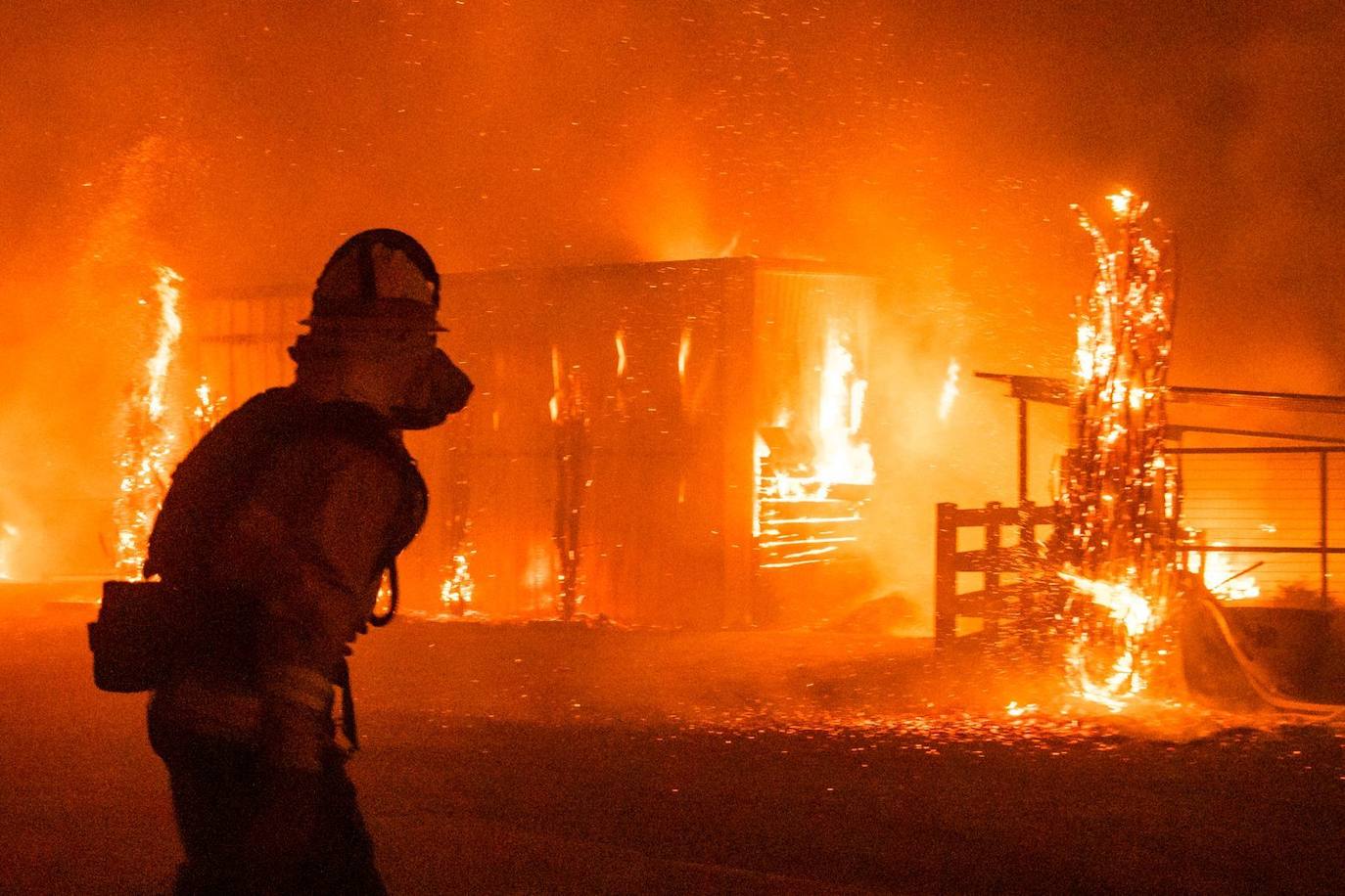 Bomberos frente a una granja en llamas durante el incendio Kincade
