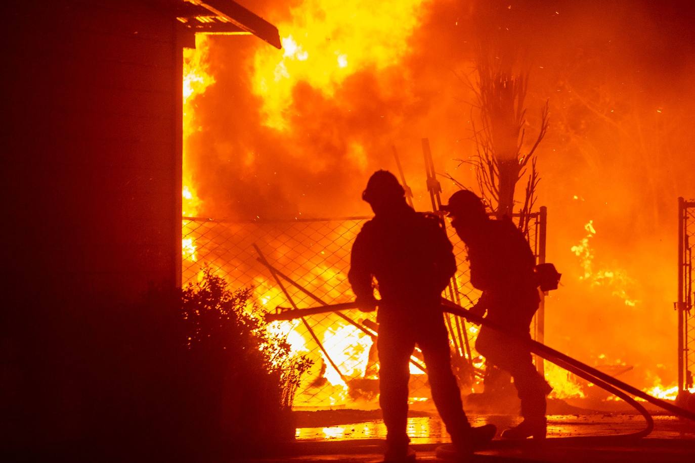 Bomberos frente a una granja en llamas durante el incendio Kincade