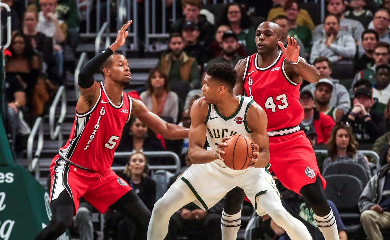 Giannis Antetokounmpo pugna con Anthony Tolliver y Rodney Hood en el partido contra Portland Trail Blazers