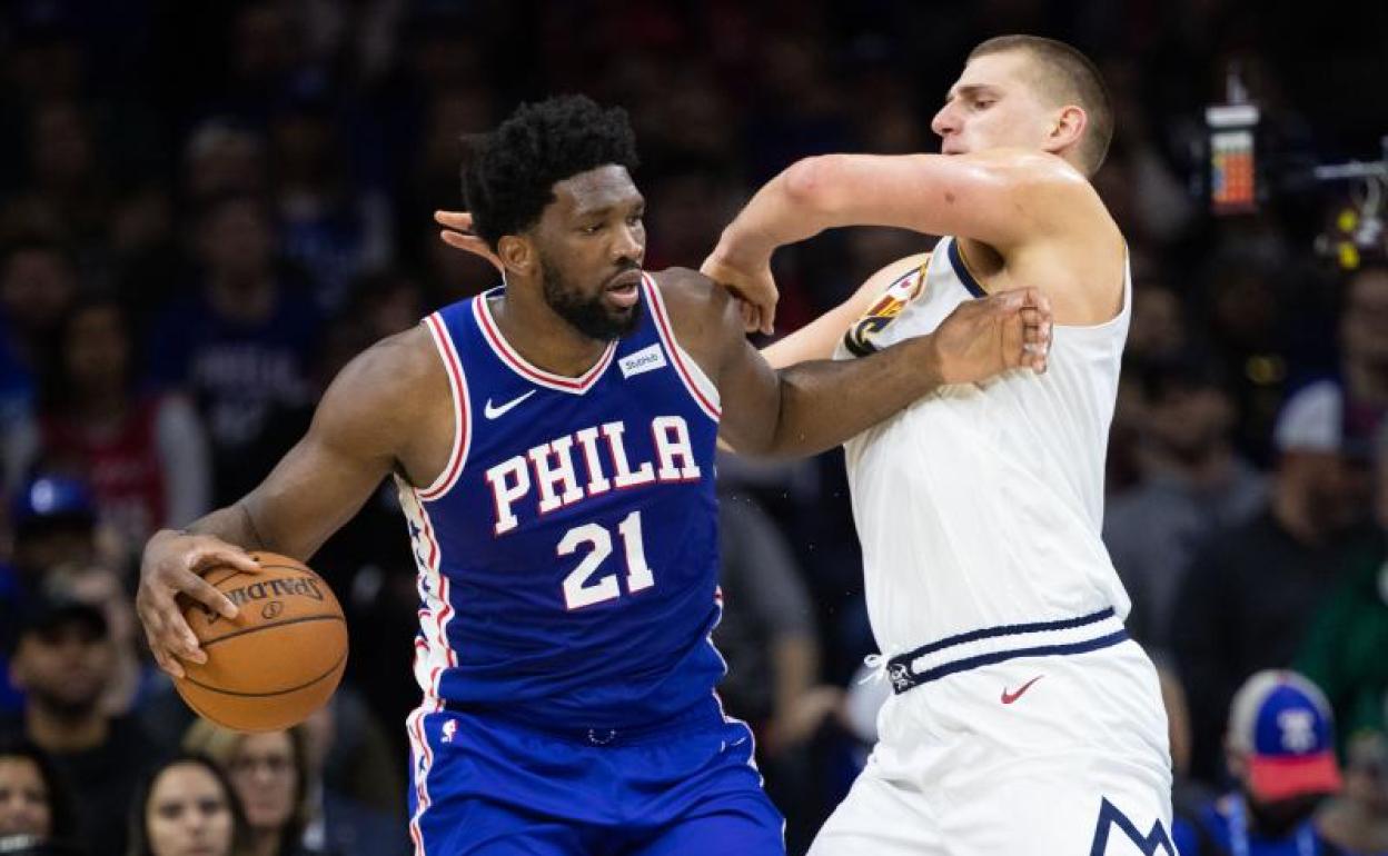 El pívot de los Sixers Joel Embiid (i), frente a Nikola Jokic. 