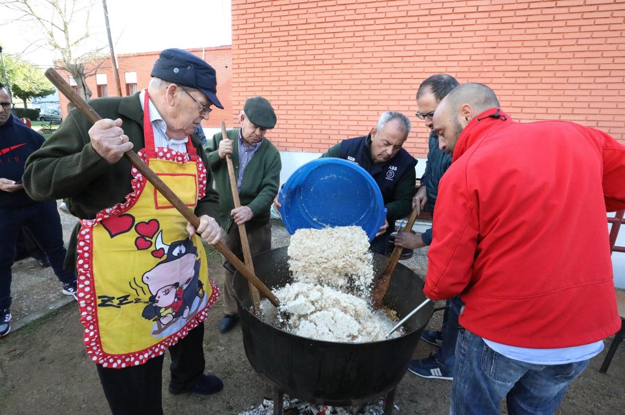 Con un llamativo y divertido delantal, Pedro Domínguez, y a su derecha, Valeriano Prida, remueven las migas en el caldero. :: brígido