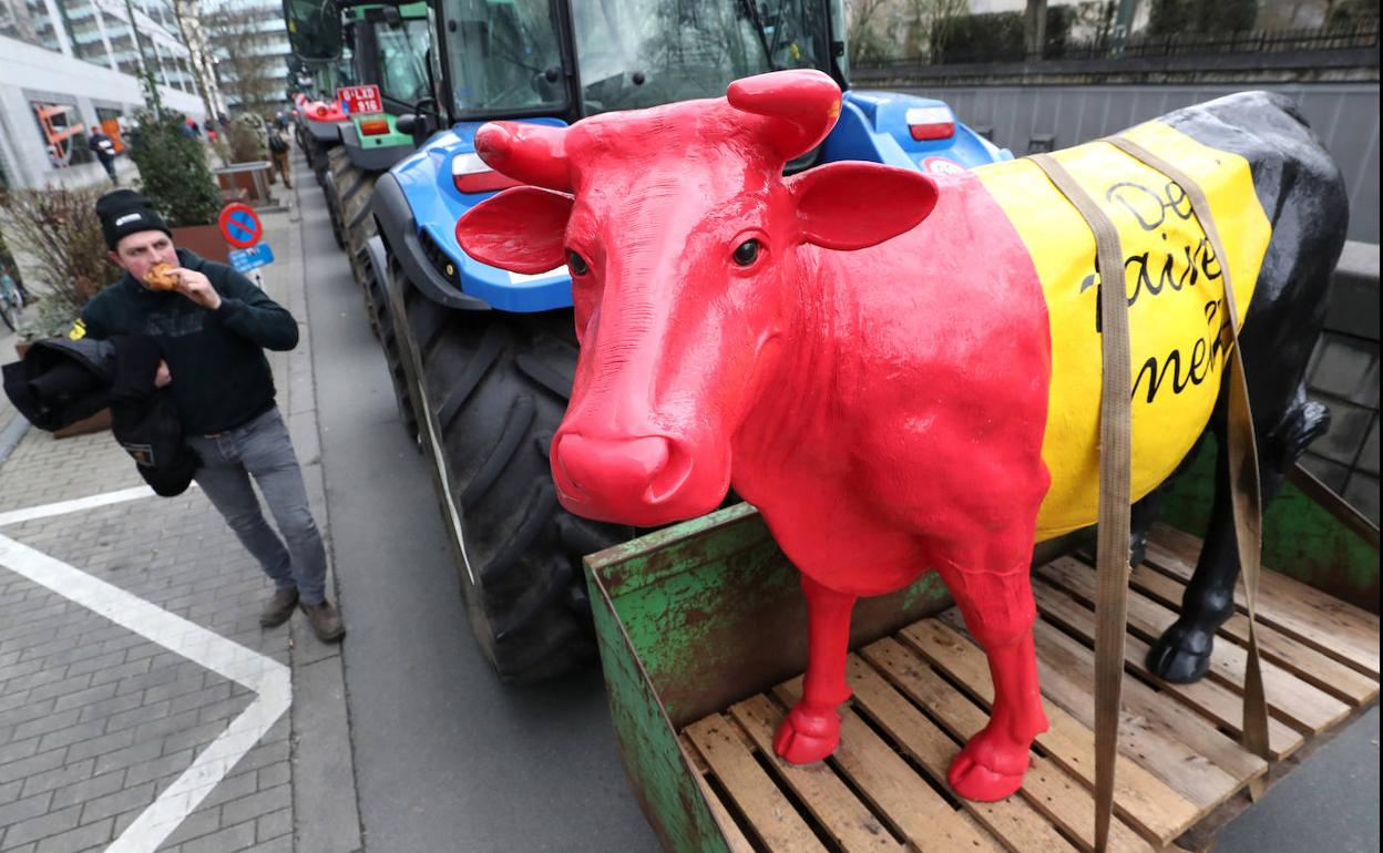 La figura de una vaca viaja en la trasera de un tractor durante una protesta de productores de leche en el exterior de la sede de las instituciones europeas en Bruselas.