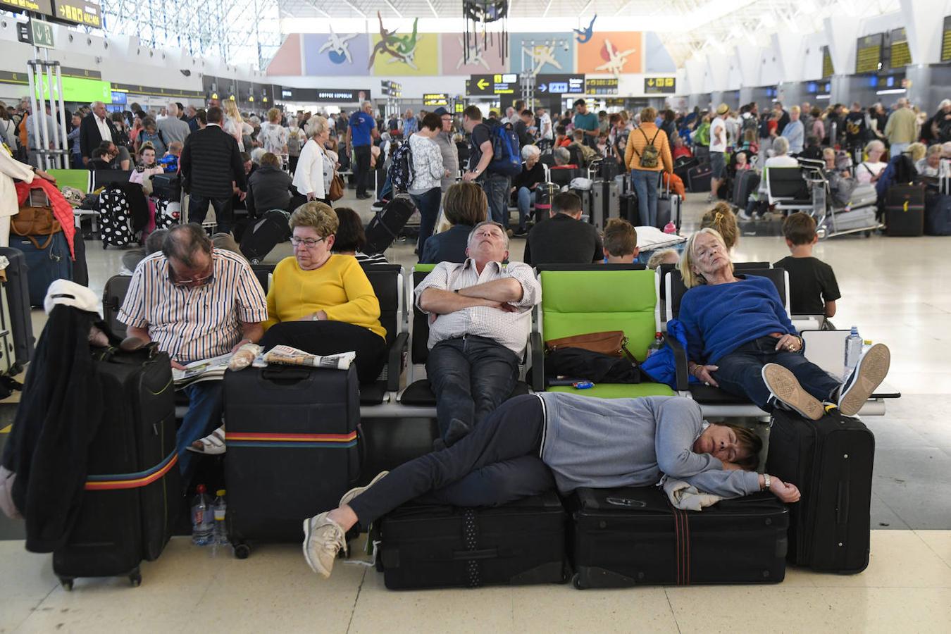 Los pasajeros tratan de dormir mientras esperan sus vuelos en el aeropuerto de Gando.