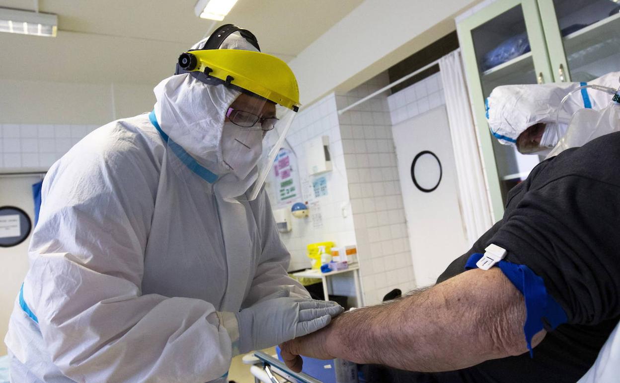 Un médico realiza un análisis de sangre a un paciente enfermo de COVID-19