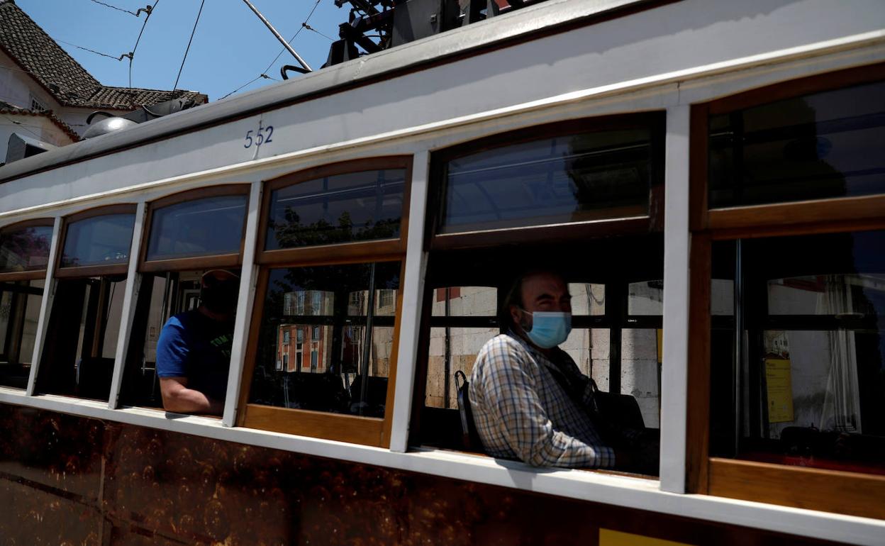 Varios pasajeros con mascarillas en un tranvía en Lisboa.