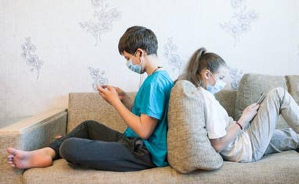 Dos adolescentes mirando el móvil y la tablet. 