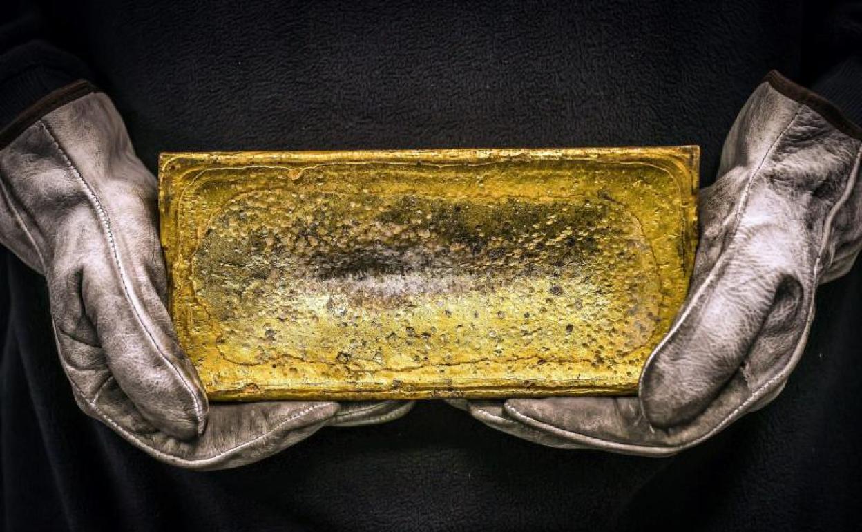 Un trabajador con un bloque de oro de 20 kilos en sus manos 