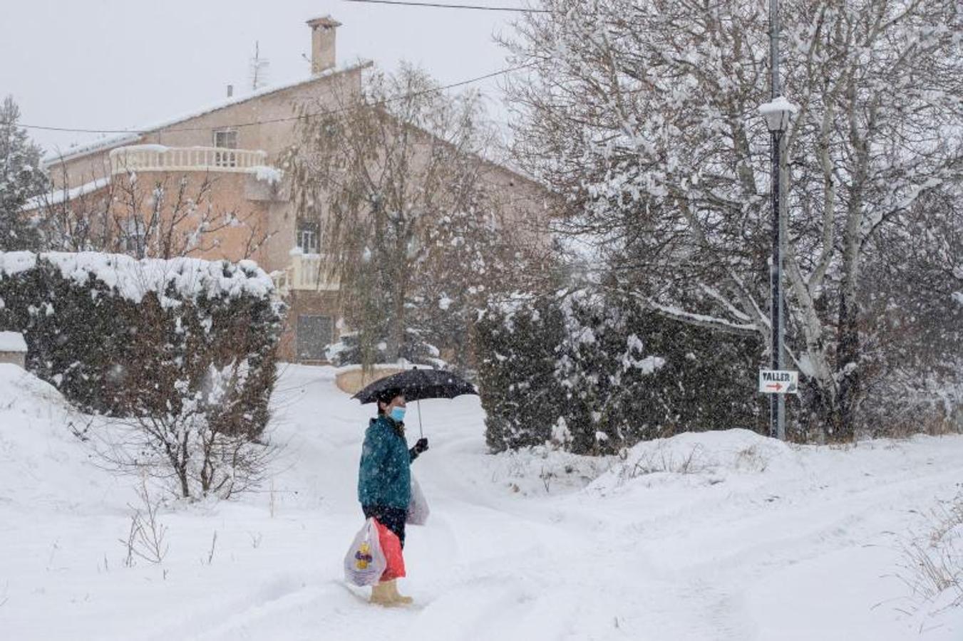 Una mujer camina en medio de una intensa nevada con una bolsa de compra este jueves en la pedanía de Campo de San Juan, Moratalla (Murcia).