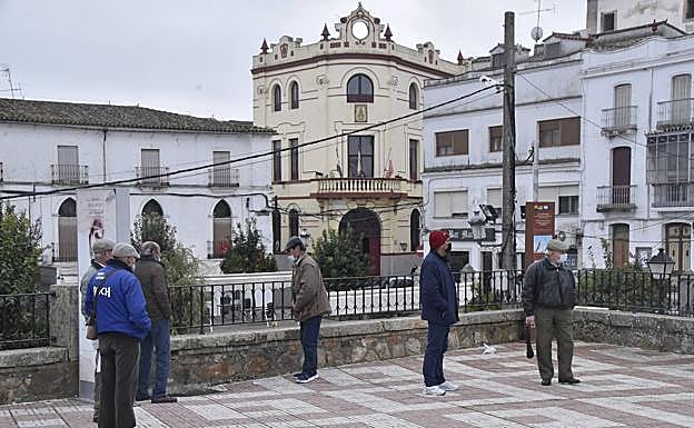 Varios jubilados pasan la mañana en la plaza de España de Alburquerque con el Ayuntamiento al fondo. 