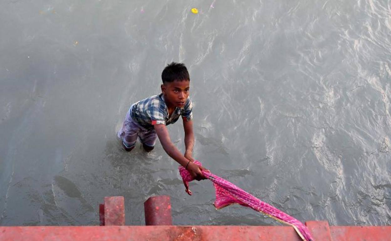 Uno de los niños buscadores de 'tesoros' sale del Ganges con la ayuda de un largo pañuelo.