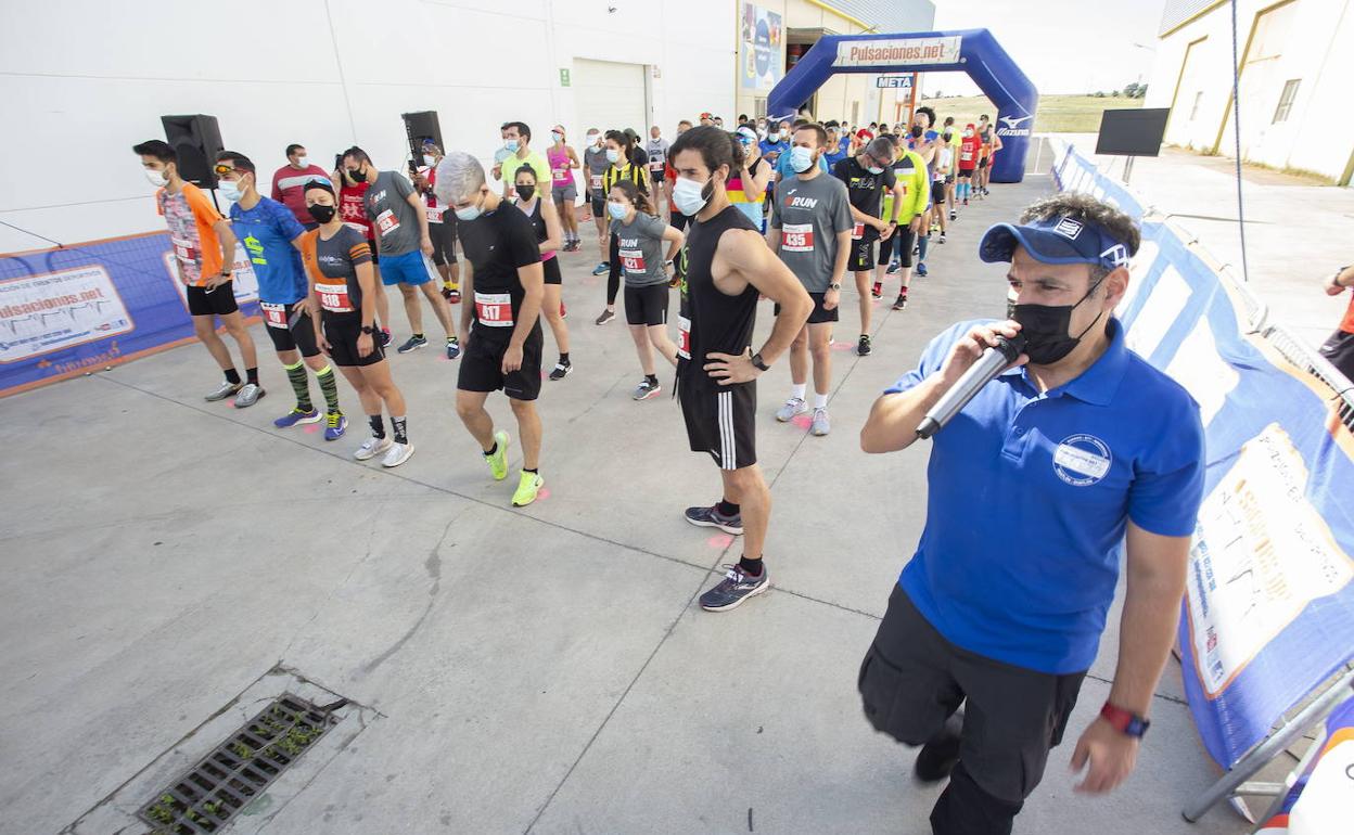 Pozas, con micrófono en mano, junto a los corredores en la línea de salida antes del inicio de la carrera. 