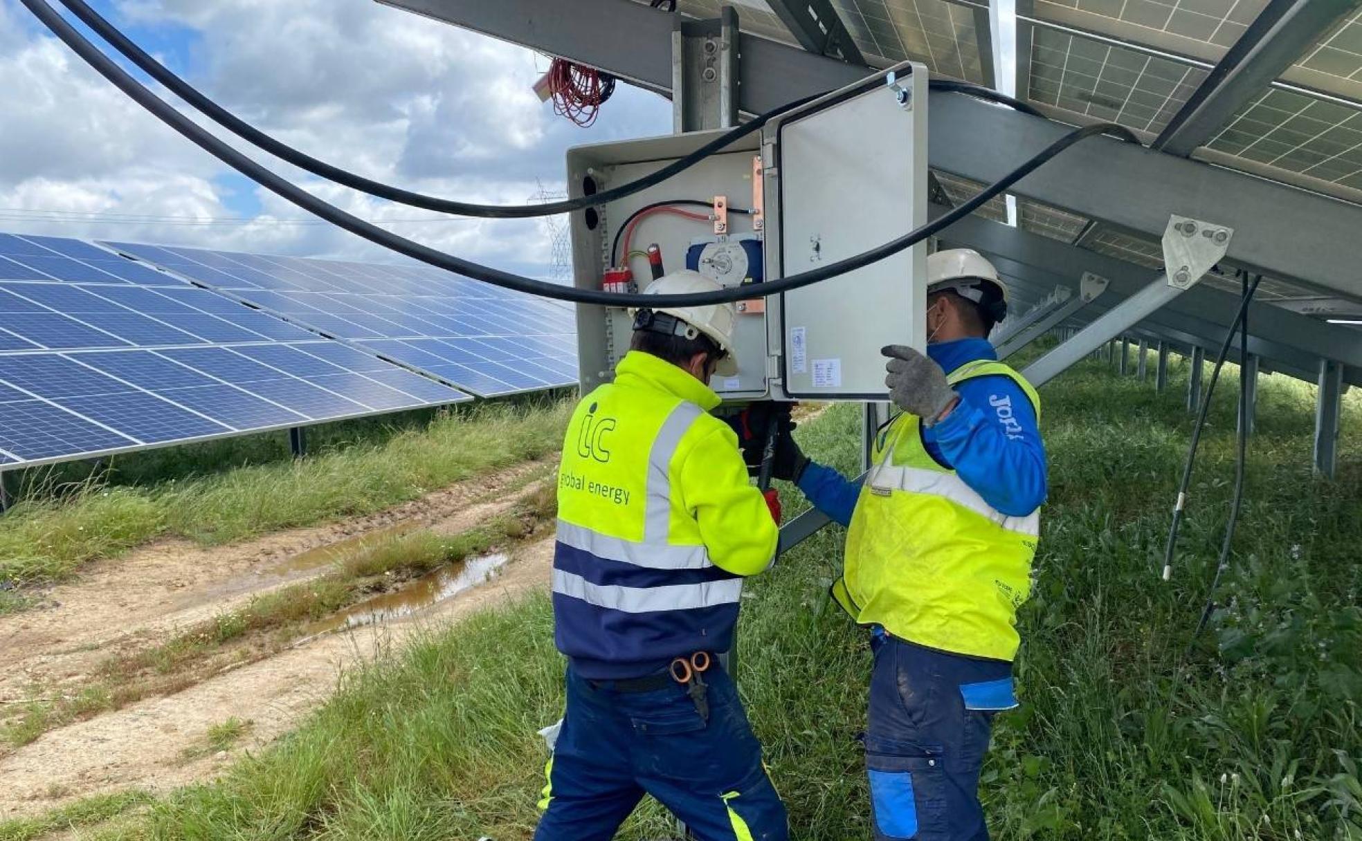 Dos operarios manipulan una de las placas fotovoltaicas en construcción. 