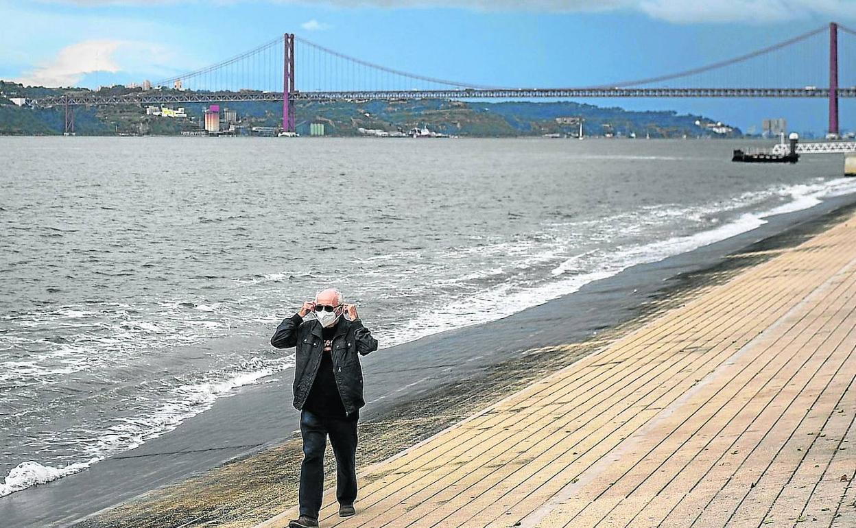 Un hombre pasea en soledad por la Ribeira das Naus en las primeras horas de cierre perimetral de Lisboa.