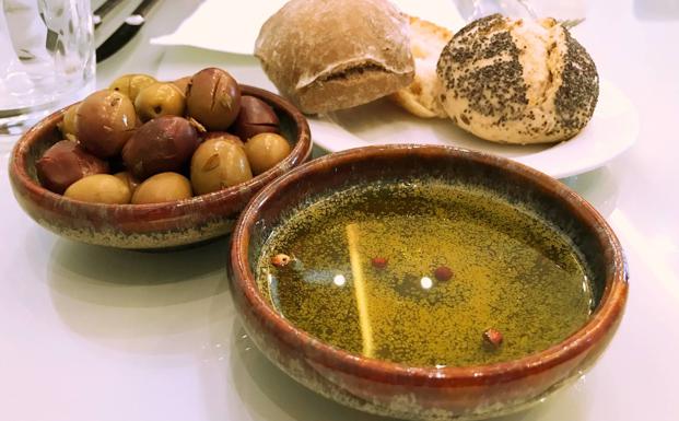 Aperitivo de aceite, panes y aceitunas.