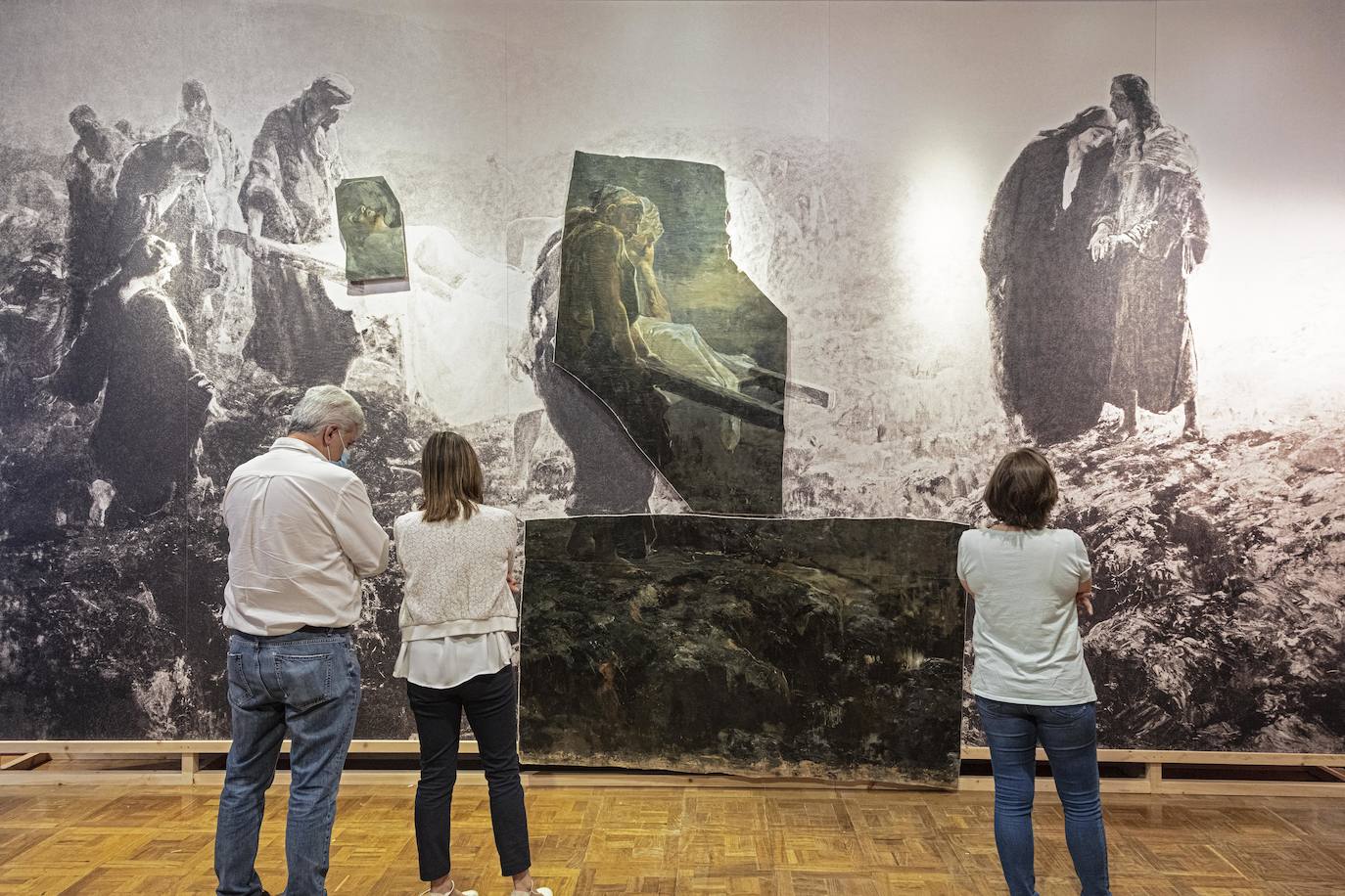 Tres personas observan la reconstrucción de 'El entierro de Cristo' (1885-1887).