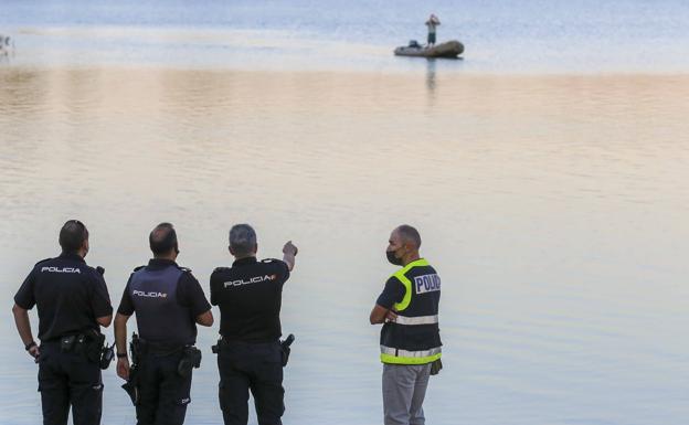 Un agente señala un punto del embalse en el que ha desaparecido el vecino de Miajadas. 