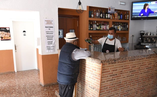 David Paquete sirve un vermut rojo a un vecino de Valdemorales, en el bar que regenta desde hace tres meses.