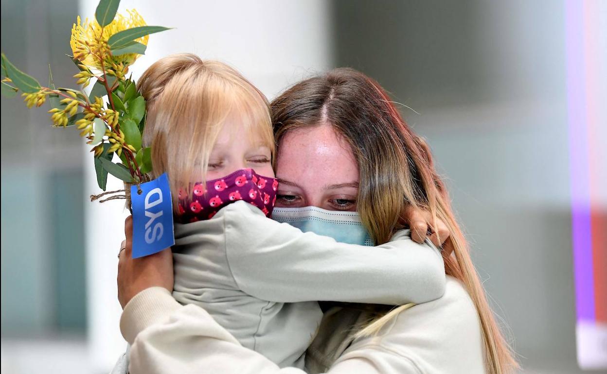Miembros de una familia se abrazan en el aeropuerto internacional de Sídney tras permanecer cerradas las fronteras desde marzo del año pasado.
