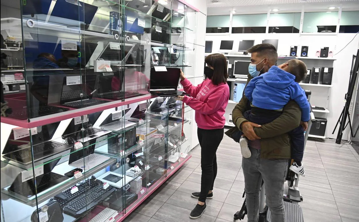 Myriam muestra un ordenador portátil a un cliente en la tienda de Cash Converter en Badajoz. 