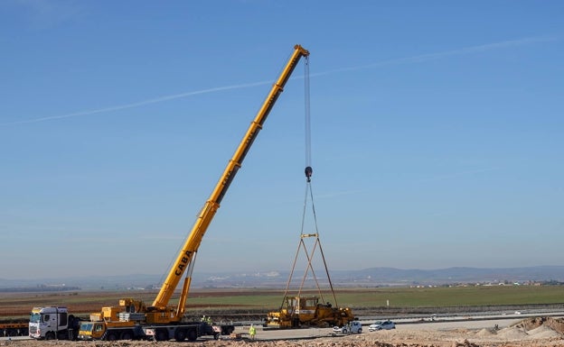 Una grúa descarga la perfiladora en las vías del tren de la plataforma logística en Badajoz. 