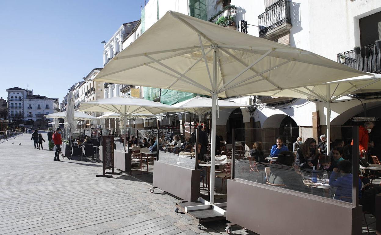 Terrazas en la Plaza Mayor de Cáceres con elementos separadores y parasoles. 
