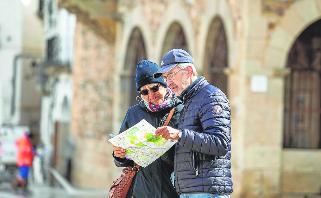 Dos turistas consultan un plano de la ciudad de Cáceres, este lunes en la Plaza Mayor. 