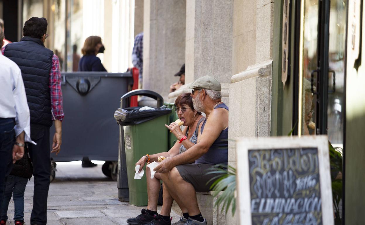 Una pareja reponiendo fuerzas en la calle Pintores este viernes. 