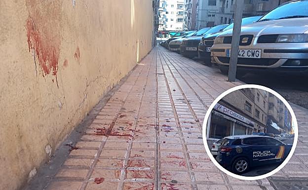 La sangre es visible en el lugar de la agresión. En el círculo, un coche de la Policía Nacional en la calle Juan XXIII . 