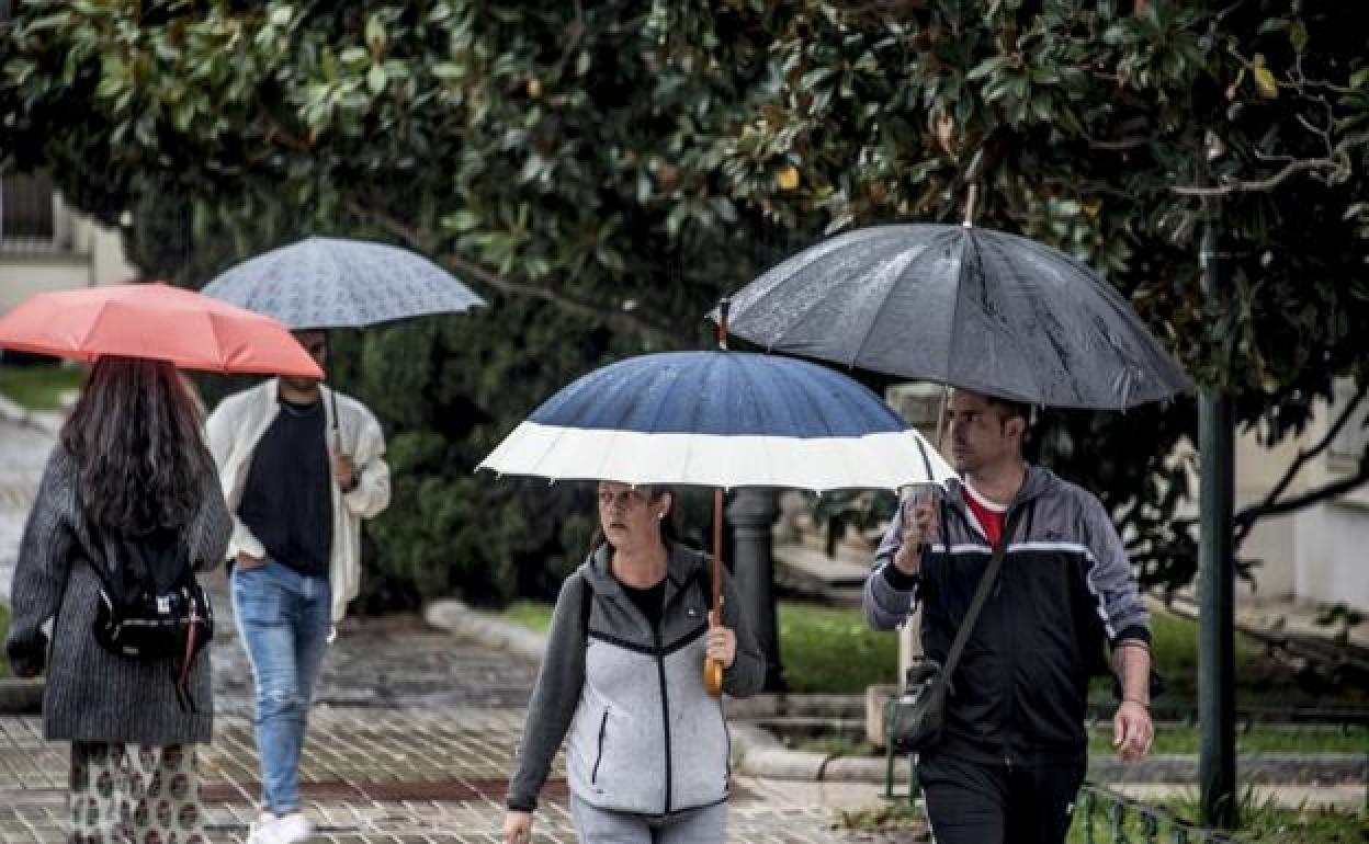 Imagen de archivo de personas paseando por Badajoz con paraguas.