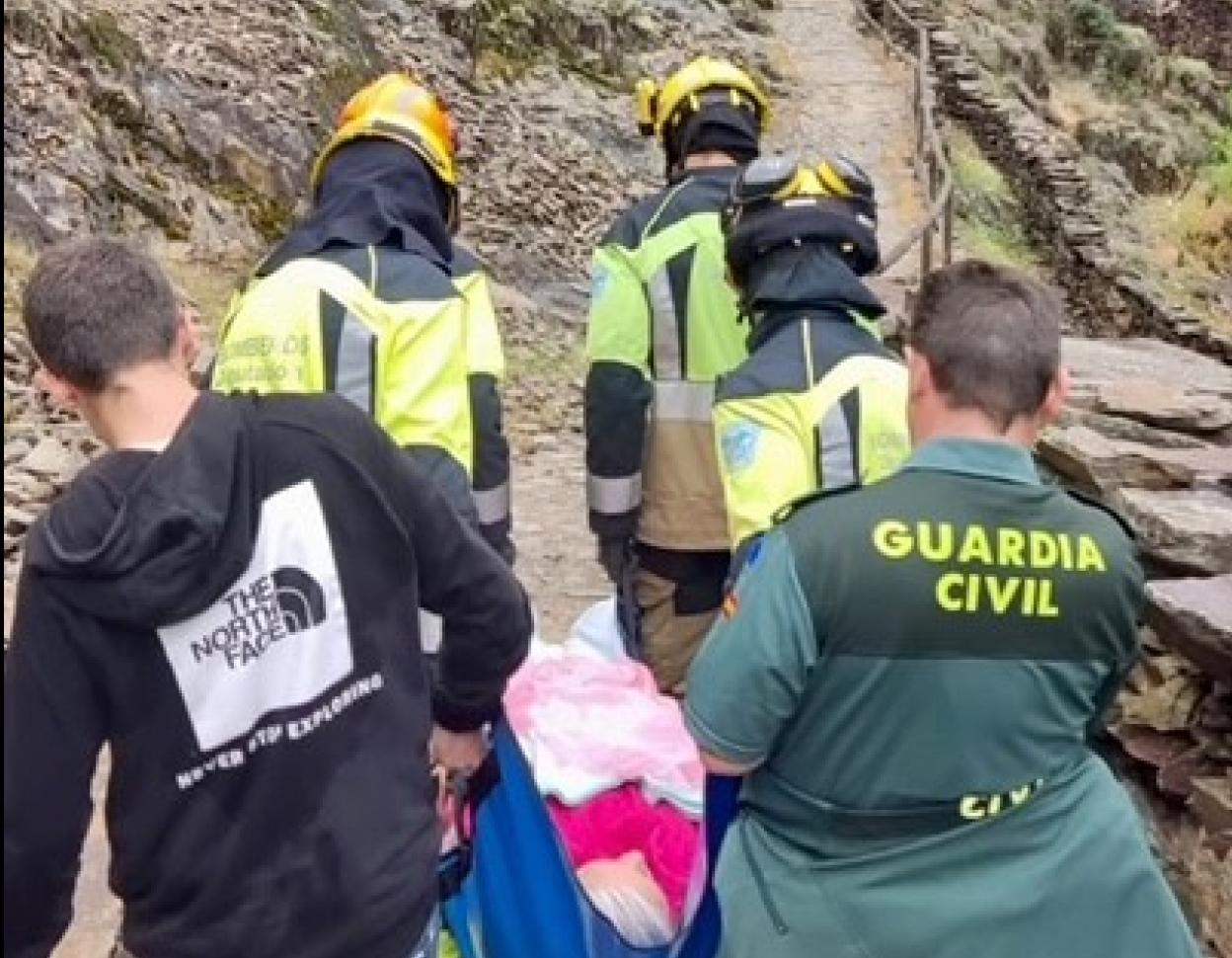 Un momento del traslado de la mujer por parte de bomberos y guardias civiles. 