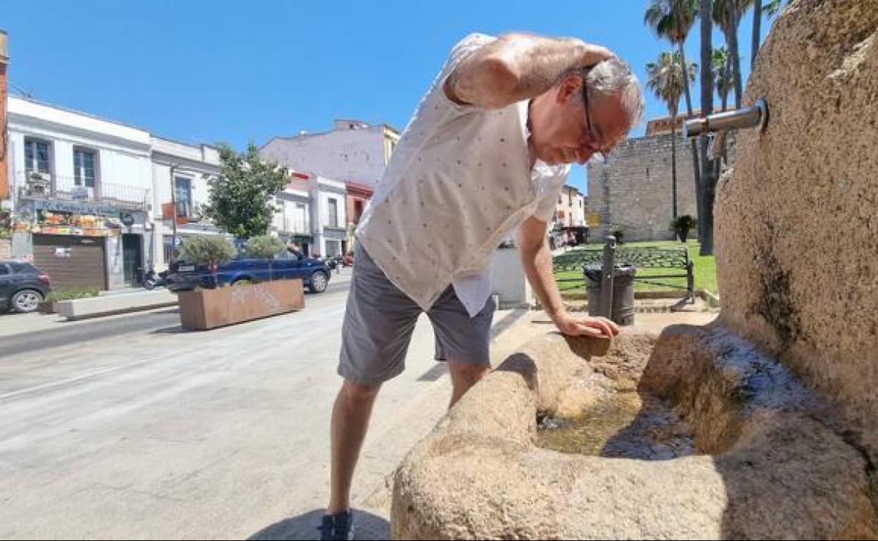 Un hombre se refresca en una fuente en Mérida.