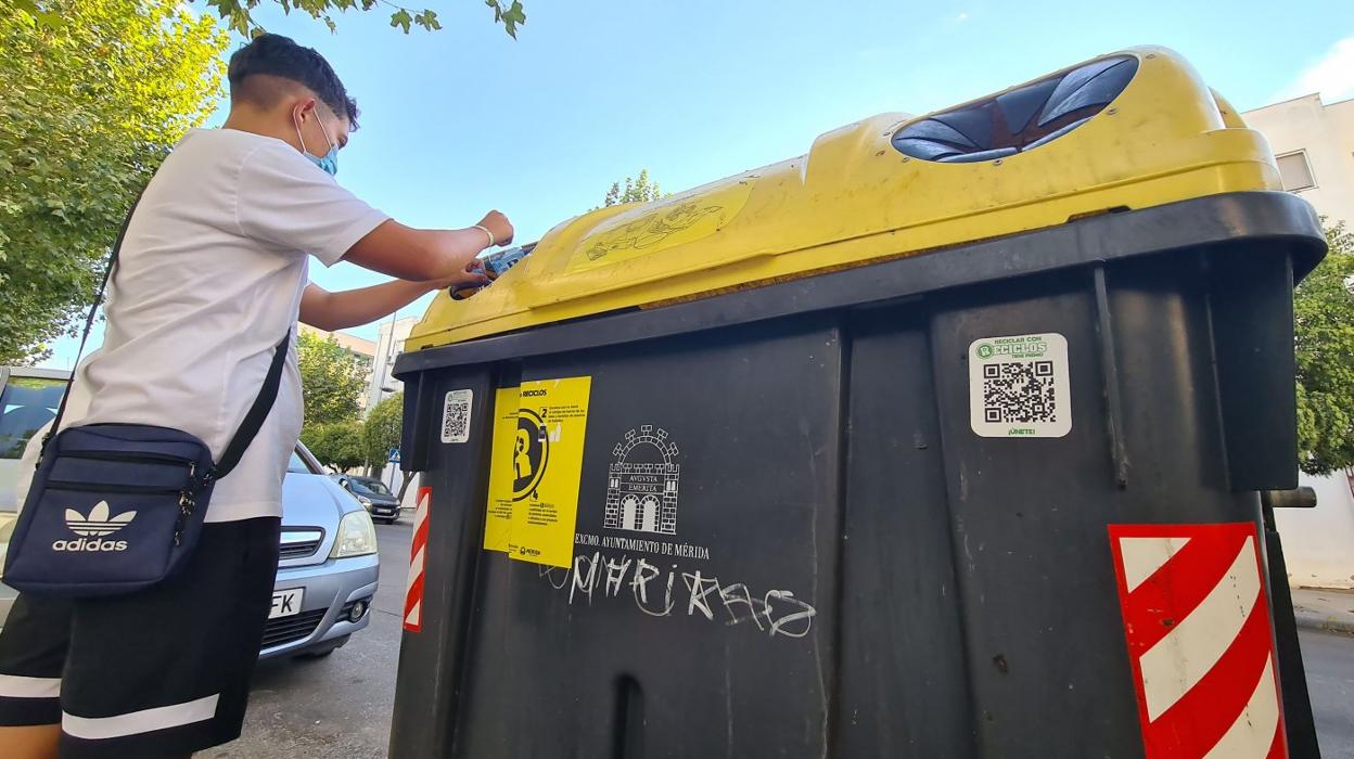 Un joven deposita una botella de plástico en un contenedor con código QR. 