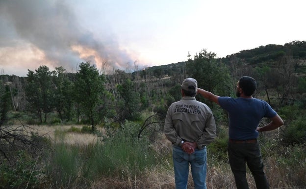 Vecinos de La Vera ven la columna de humo del incendio declarado el viernes en Vilanueva de La Vera. 