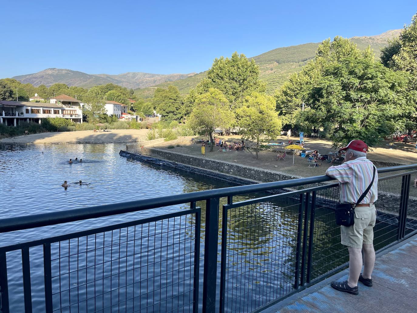 Un hombre observa la piscina Simón desde el paso peatonal.