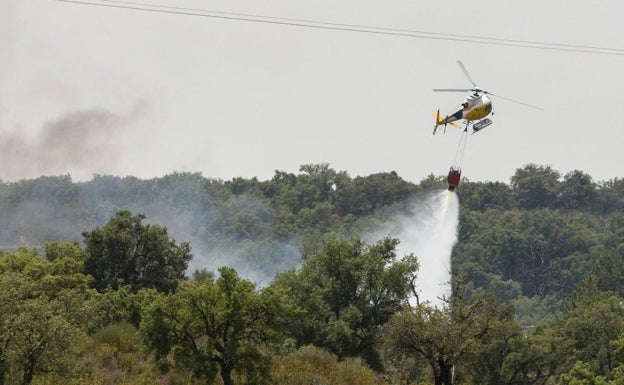 Un helicóptero vierte agua sobre las llamas, en el incendio de Casas de Miravete.