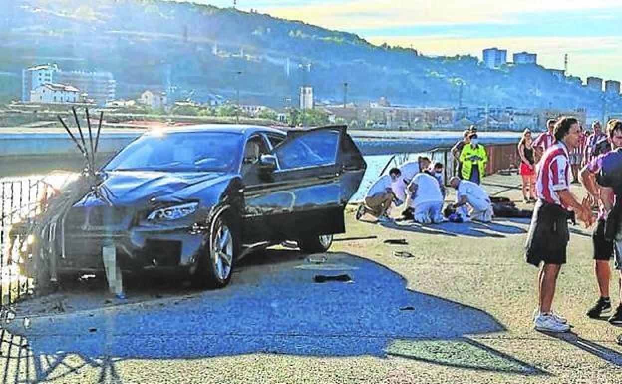 Sanitarios atienden a la víctima instantes después de ser arrollada por el coche, que a punto estuvo que caer a la ría..