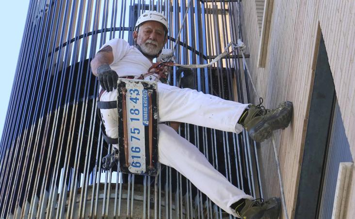 Juan Carlos Carmona pintando una ventana de Mérida atado a un arnés.