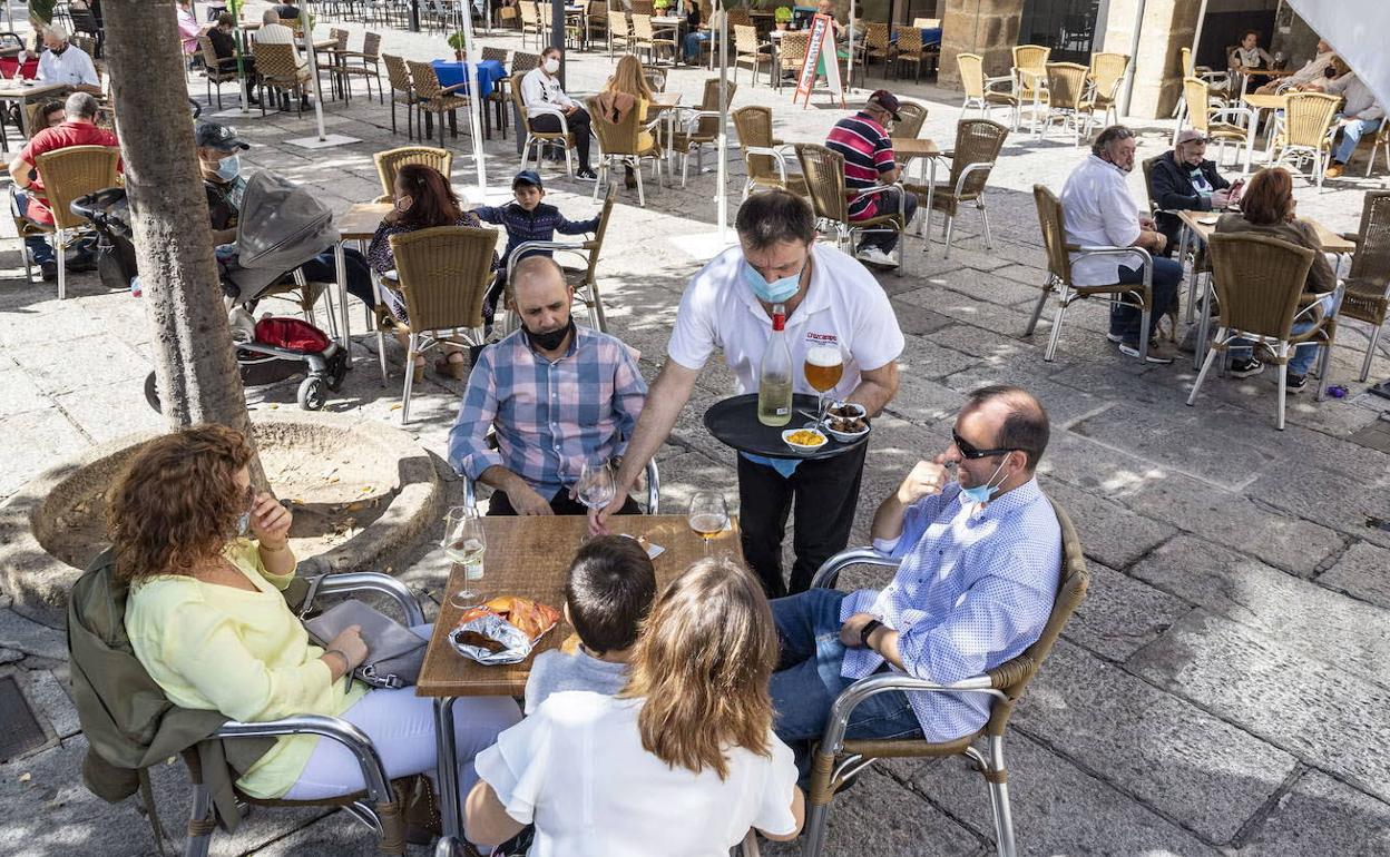 Un camarero atiende a los clientes en una terraza. 