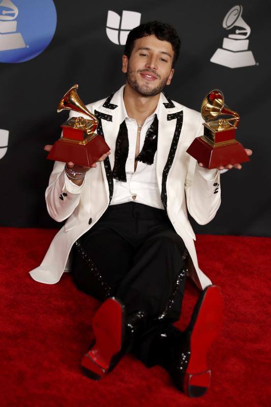 Sebastian Yatra posa en el suelo con sus dos premios. 