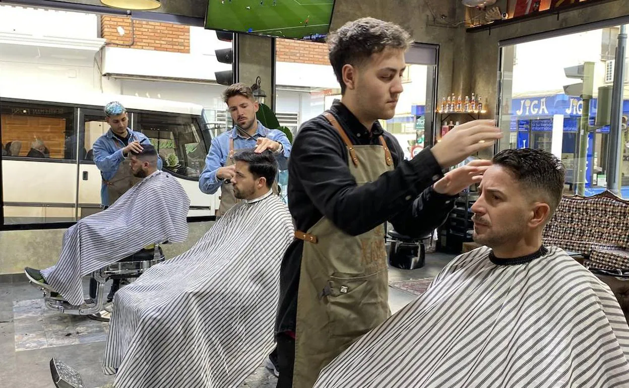 David, en el centro, junto a dos barberos más y los clientes. 