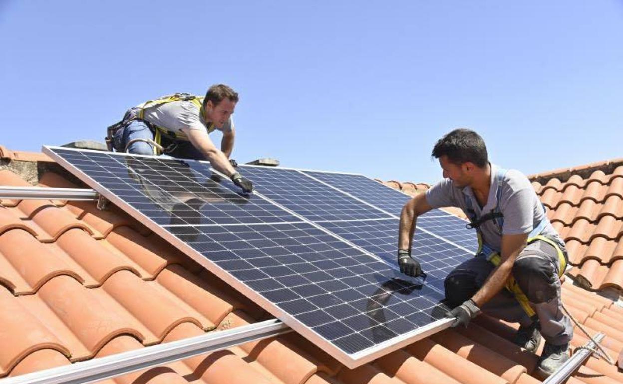 Dos operarios instalan placas solares en el tejado de una vivienda en una imagen de archivo. 